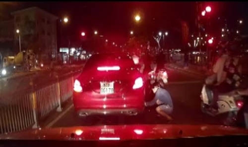 Một thanh niên đang cạy lấy trộm logo của xe Mercedes vào tối 4.8 khi xe dừng chờ đèn đỏ tại giao lộ Bến Vân Đồn – Khánh Hội (Q.4) – Ảnh: Internet