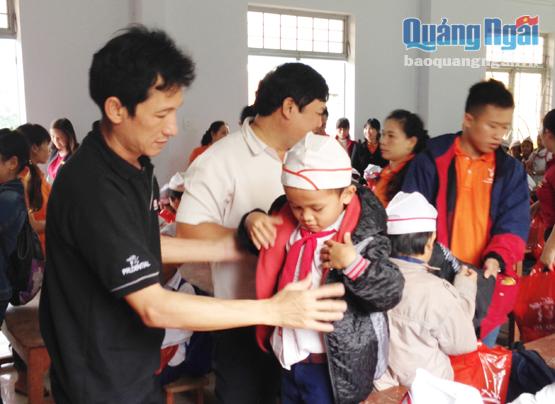 Thành viên đoàn tình nguyện mặc áo ấm cho trẻ em xã Ba Điền (Ba Tơ).
