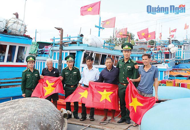 Đại úy Nguyễn Quang Vinh (thứ 3 từ trái qua) cùng với cán bộ Đồn Biên phòng Lý Sơn tặng cờ Tổ quốc cho ngư dân Lý Sơn.