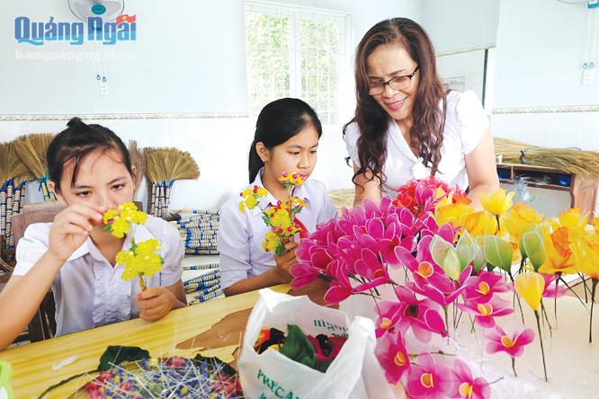 Cô Trần Thị Thu Thủy hướng dẫn cho trẻ khuyết tật cách làm hoa voan.