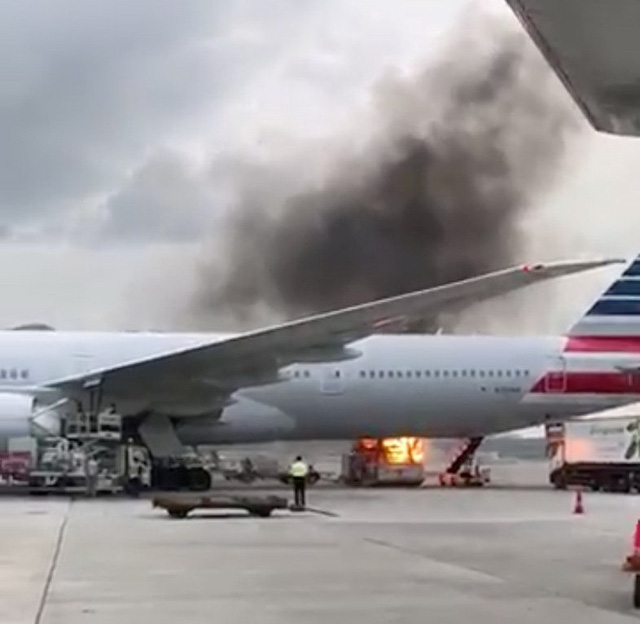   Một phương tiện hoạt động ở đường băng sân bay quốc tế Hong Kong phát cháy gần chiếc máy bay của Hãng American Airlines - Ảnh: REUTERS