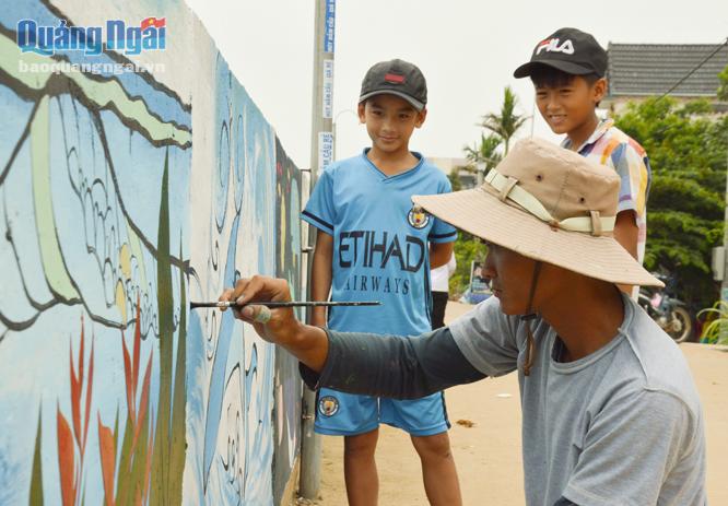  Thành viên của nhóm tình nguyện đang vẽ tranh tuyên truyền bảo vệ môi trường biển ở thôn Định Tân, xã Bình Châu (Bình Sơn).