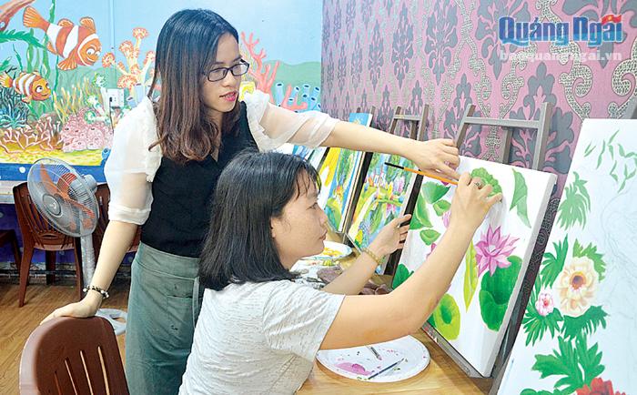 Chị Phan Thị Xuân Vi (đứng) đang hướng dẫn học viên hoàn thành một bức vẽ.