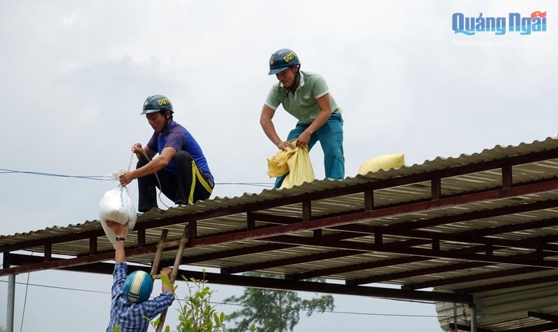 Chính quyền địa phương hỗ trợ người dân đưa những bao cát lên gia cố mái nhà 