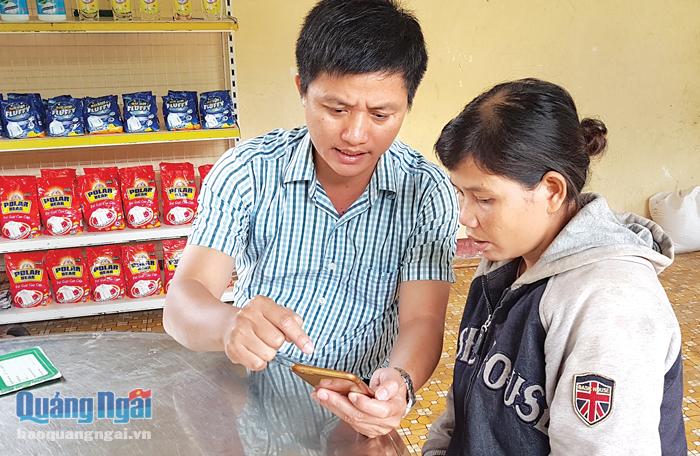 Cán bộ tín dụng Ngân hàng CSXH huyện Trà Bồng hướng dẫn hộ vay cài đặt và sử dụng phần mềm giáo dục tài chính trên điện thoại.