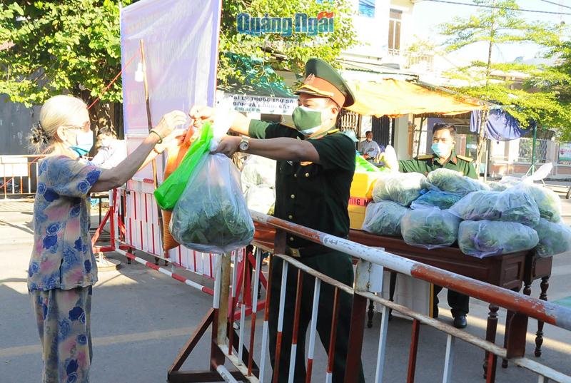 Người dân ở khu phong tỏa chợ Hàng Rượu, phường Trương Quang Trọng nhận quà của Ban CHQS  TP.Quảng Ngãi.  Ảnh: X.BẢO