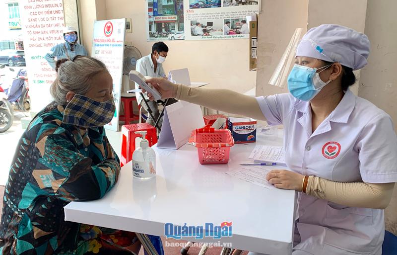 Nhân viên Phòng khám Đa khoa Minh Quang (TP.Quảng Ngãi) kiểm tra thân nhiệt người dân trước khi vào khám bệnh.