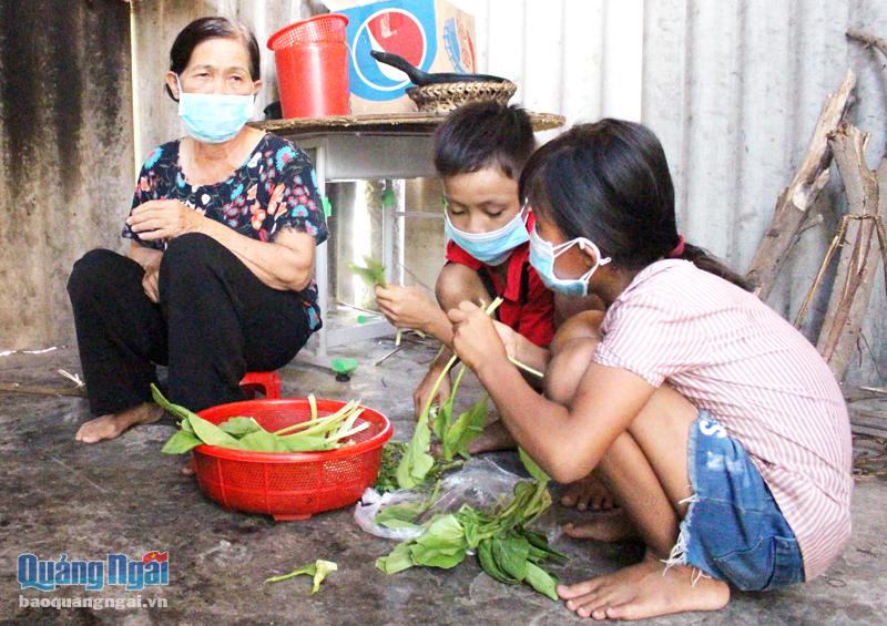 Bà Huỳnh Thị Thường, ở xã Nghĩa Mỹ (Tư Nghĩa), cùng các cháu ngoại trong căn bếp dựng tạm bợ. 