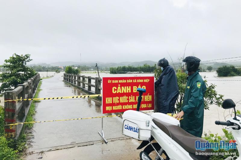 Công an huyện Bình Sơn tham gia chốt chặn tại một điểm ngập sâu ở xã Bình Hiệp. Ảnh: ĐỨC MINH