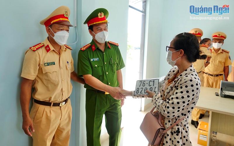 Đại tá Hoàng Anh Tuấn, Phó Giám đốc Công an tỉnh Quảng Ngãi chúc mừng công dân đầu tiên nhận biển số xe được cấp tại Công an xã Bình Dương. 