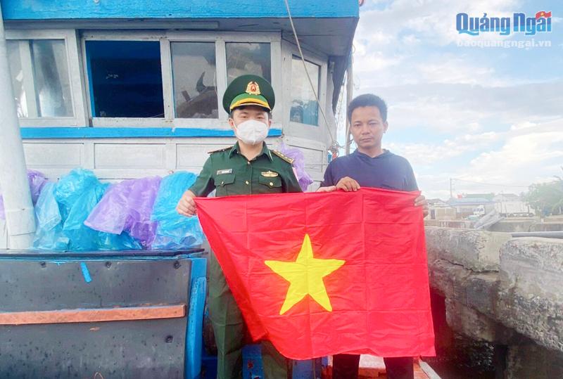 Trạm trưởng Trạm Kiểm soát Biên phòng Sa Kỳ Phan Xuân Huề tặng cờ Tổ quốc cho ngư dân tiêu Minh Hạnh, ở xã Bình Châu (Bình Sơn).