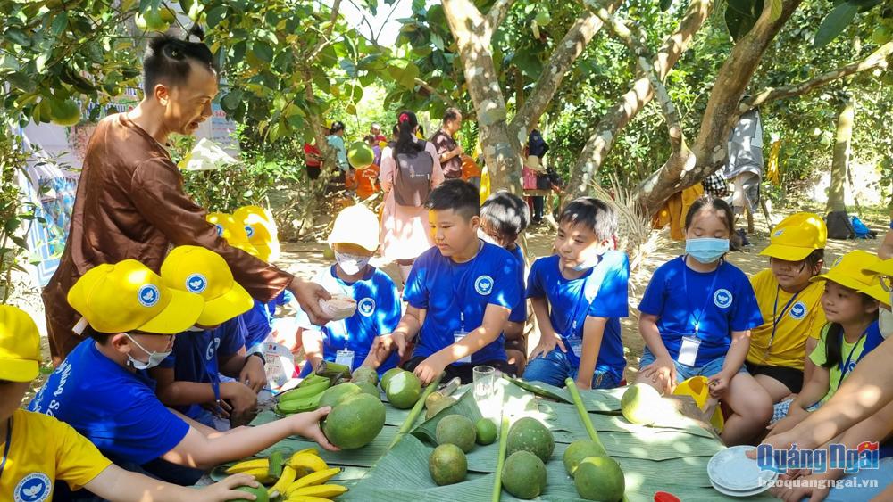 Học sinh được các nông dân phục vụ trải nghiệm vườn cây ăn quả ở Làng du lịch cộng đồng Bình Thành, xã Hành Nhân (Nghĩa Hành). Ảnh: Trí Phong