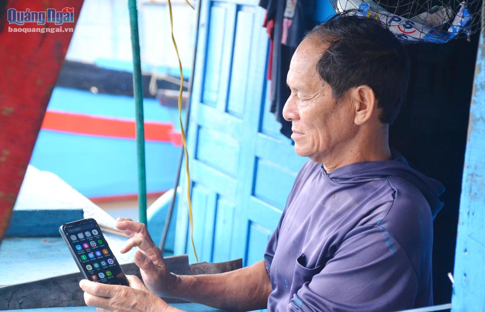 Ngư dân sử dụng điện thoại để thực hiện thủ tục cấp giấy chứng nhận an toàn kỹ thuật tàu cá.   