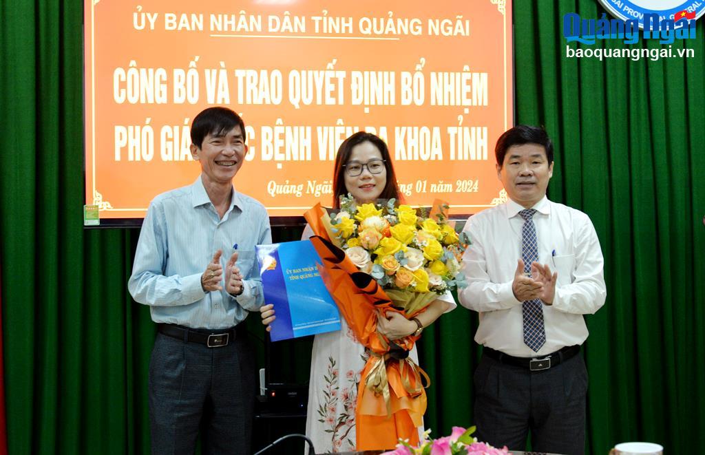 Giám đốc Sở Y tế Phạm Minh Đức và Giám đốc Sở Nội vụ Tạ Công Dũng trao quyết định và tặng hoa chúc mừng bà Đoàn Thị Xuân Mỹ.
