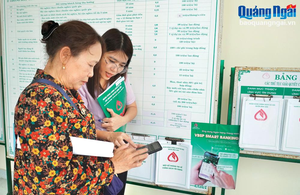Cán bộ tín dụng Phòng Giao dịch Ngân hàng Chính sách xã hội huyện Bình Sơn hướng dẫn khách hàng cài đặt VBSP Smart Banking.