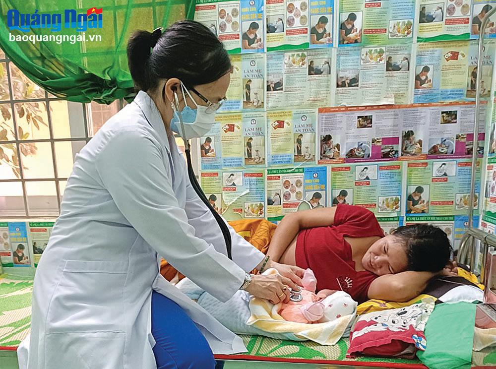 Bác sĩ Nguyễn Thị Ngọc - Trưởng Trạm Y tế xã Ba Tiêu (Ba Tơ) thăm khám cho mẹ và bé sinh tại trạm y tế.                                                        ẢNH: BẢO HÒA
