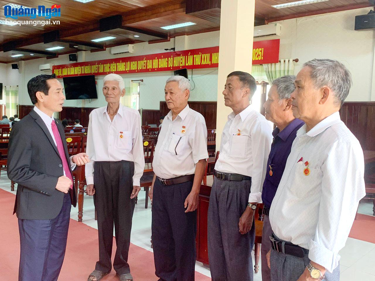Bí thư Huyện ủy Tư Nghĩa Trần Quang Tòa (bên trái) trao đổi với các đảng viên nhận Huy hiệu 40 năm tuổi Đảng.