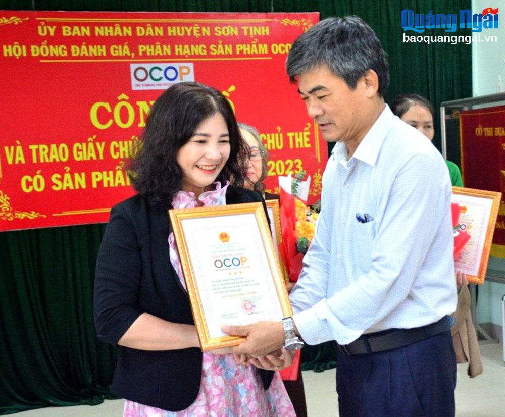 Lãnh đạo huyện Sơn Tịnh trao giấy chứng nhận OCOP 3 sao đối với sản phẩm “Bánh chưng MY TON” của chị Tôn Thị Quỳnh My.
