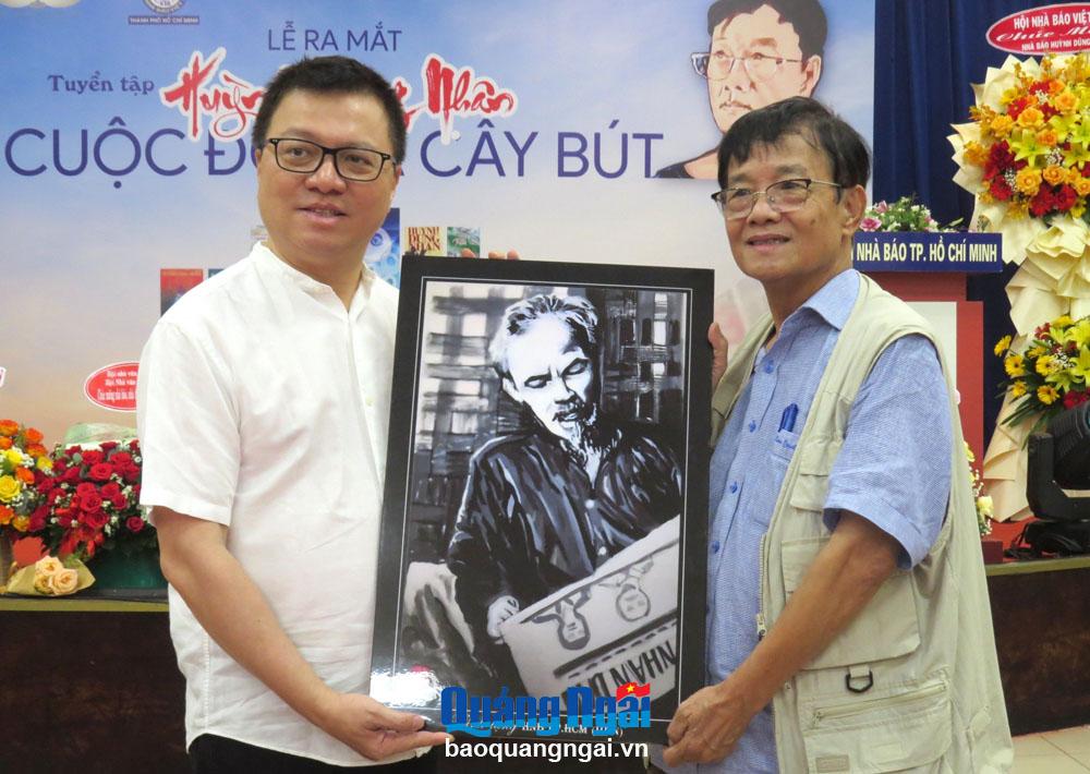 Chủ tịch Hội Nhà báo Việt Nam Lê Quốc Minh (bên trái) đón nhận tranh do nhà báo Huỳnh Dũng Nhân tặng tại buổi ra mắt tuyển tập. 