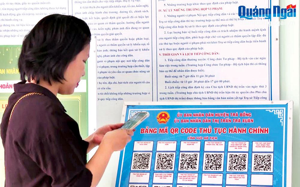 Người dân sử dụng điện thoại thông minh thực hiện quét mã QR để làm các thủ tục hành chính tại Bộ phận một cửa thị trấn Trà Xuân (Trà Bồng).