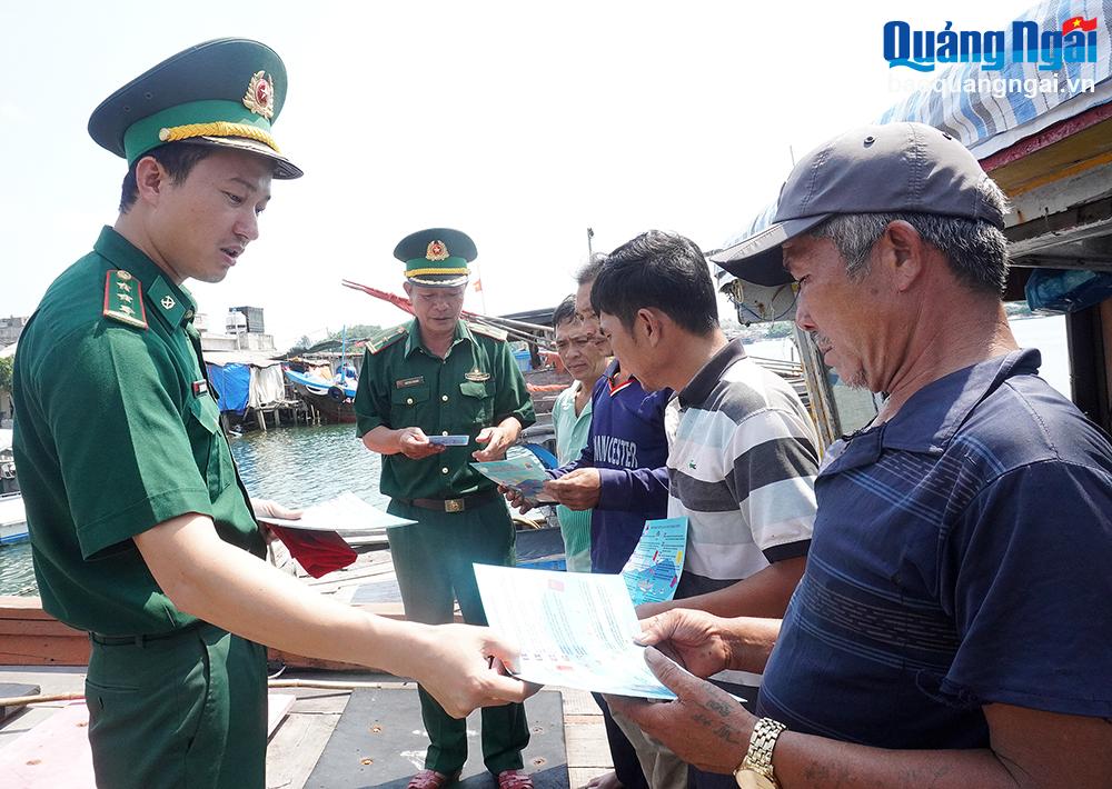 Cán bộ Đồn Biên phòng Bình Thạnh (Bình Sơn) phát tờ rơi tuyên truyền về chống khai thác IUU cho ngư dân trước khi tàu xuất bến.

