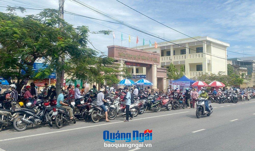 Thành viên Câu lạc bộ truyền thông Trường THPT Số 1 Tư Nghĩa hỗ trợ sắp xếp xe máy gọn gàng trước cổng trường.