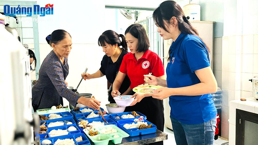 Đoàn viên Chi Đoàn Báo Quảng Ngãi phụ đảng viên Nguyễn Thị Hường sửa soạn bữa ăn trưa cho các cháu. Ảnh: CĐ