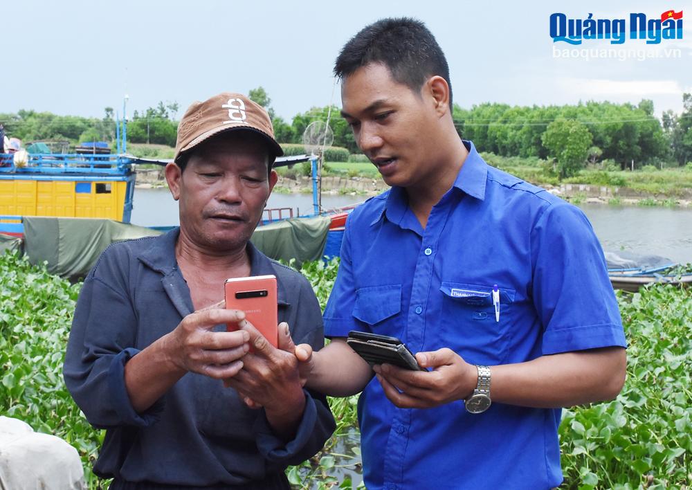 Thành viên Tổ công nghệ số cộng đồng xã Nghĩa Phú (TP.Quảng Ngãi) hướng dẫn ngư dân về dịch vụ công trực tuyến.  Ảnh: LAM GIANG