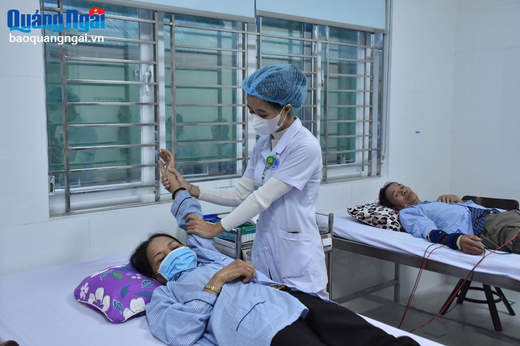 Kỹ thuật viên Khoa Y học cổ truyền và Phục hồi chức năng (Trung tâm Y tế huyện Bình Sơn) hỗ trợ bệnh nhân phục hồi chức năng.