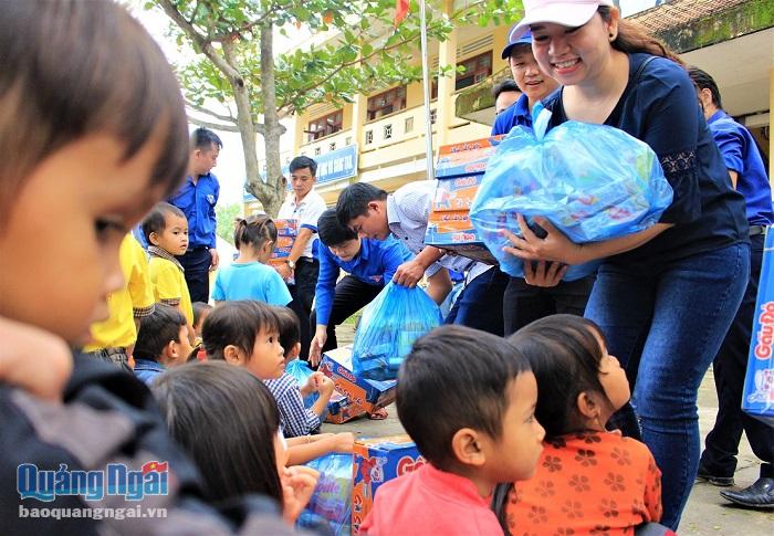 Chị Phương Uyên trao quà của nhóm nhà báo trẻ ở 3 miền đến các em học sinh vùng lũ tại KDC Nước Nia, T.T Di Lăng (Sơn Hà).