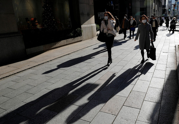 Người đi bộ qua một cửa hàng giữa đại dịch COVID-19 ở Tokyo, Nhật Bản ngày 25-12-2020 - Ảnh: REUTERS