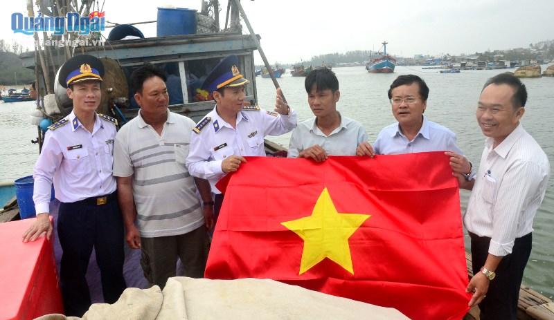 Cảnh sát biển và Ban Dân vận Tỉnh uỷ tặng cờ Tổ quốc và quà Tết cho tàu cá của anh Trần Chinh.