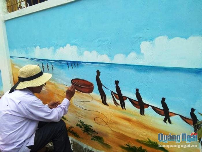 Họa sĩ vẽ tranh trên tường ở nhà văn hóa thôn Hải Ninh.