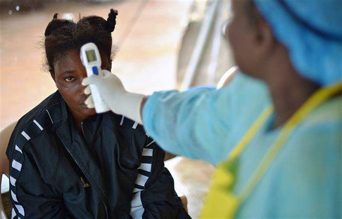 Nhân viên y tế kiểm tra thân nhiệt bệnh nhân nghi nhiễm virus Ebola tại Kenema, Guinea. Ảnh: AFP/TTXVN