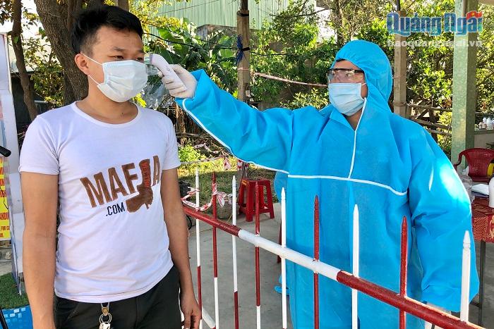 Kiểm tra thân nhiệt cho người dân khi đi qua chốt kiểm tra y tế trên Quốc lộ 1 đoạn qua Dốc Sỏi, huyện Bình Sơn