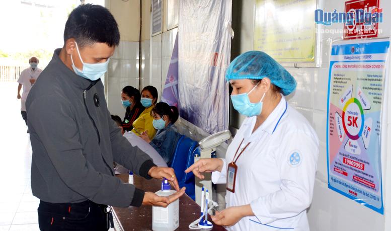 Nhân viên y tế Trung tâm Y tế huyện Tư Nghĩa hướng dẫn người dân sát khuẩn tay trước khi khám bệnh.