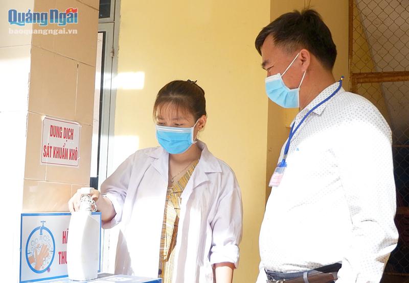 Phó Trưởng điểm thi Trường THPT Huỳnh Thúc Kháng Đỗ Tấn Ngọc kiểm tra việc bố trí dung dịch rửa tay sát khuẩn tại các phòng thi.              Ảnh: ĐĂNG SƯƠNG