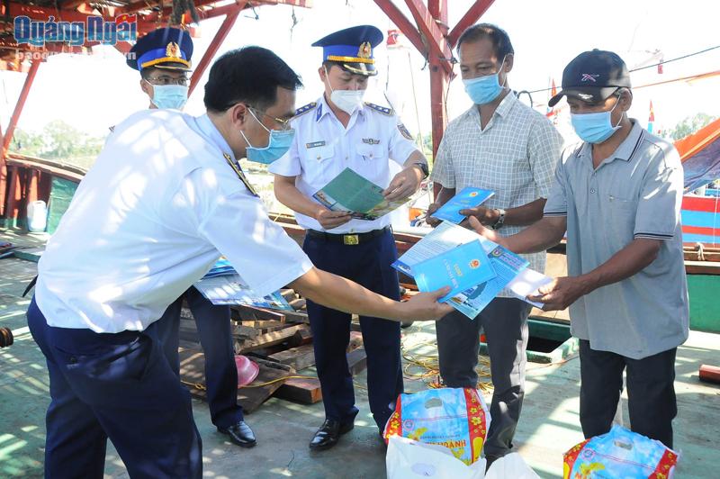 Cán bộ, chiến sĩ Vùng Cảnh sát biển 2 phát tài liệu tuyên truyền cho ngư dân xã Bình Chánh (Bình Sơn). 