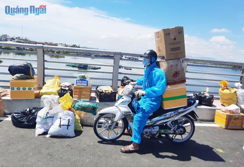 Thanh niên tình nguyện xã Nghĩa An (TP.Quảng Ngãi) vận chuyển hàng hóa thiết yếu từ điểm tập kết đến nhà người dân trong vùng  phong tỏa.  