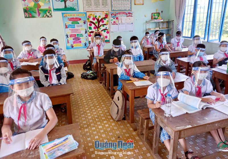 Học sinh Trường Tiểu học Long Hiệp (Minh Long) mang mặt nạ gương chống giọt bắn để phòng, chống dịch trong giờ học.