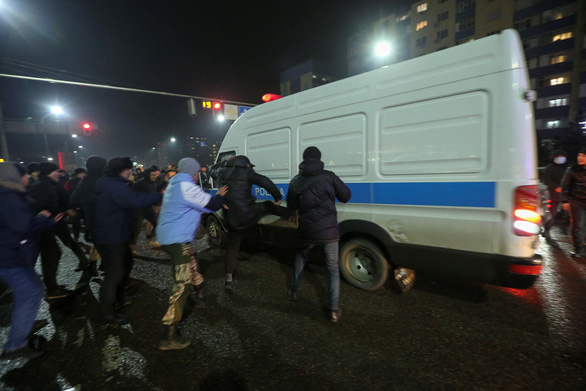Người biểu tình tấn công xe cảnh sát ở thành phố Almaty, Kazakhstan - Ảnh: REUTERS