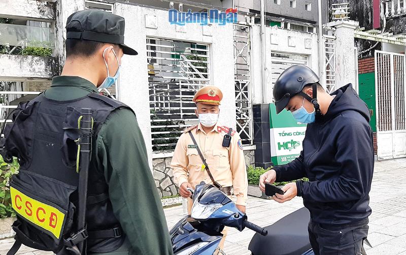 Cán bộ, chiến sĩ Phòng Cảnh sát giao thông (Công an tỉnh) kiểm tra giấy tờ của người điều khiển xe máy.  Ảnh: Bá Sơn
