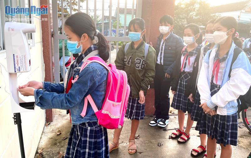 Học sinh Trường THCS Quảng Phú (TP.Quảng Ngãi) đo thân nhiệt và sát khuẩn trước khi vào lớp học. 
