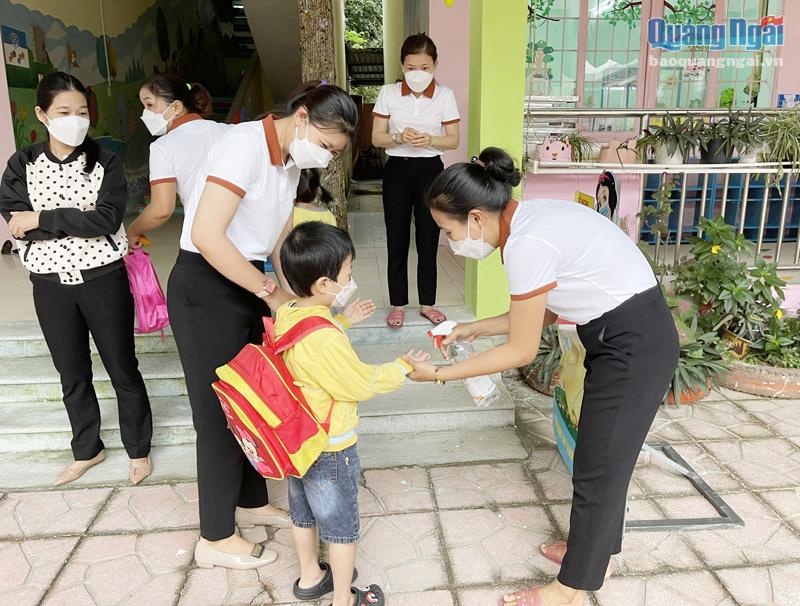 Giáo viên Trường Mầm non 19/5 (TP.Quảng Ngãi) sát khuẩn tay cho học sinh trước khi vào lớp học.