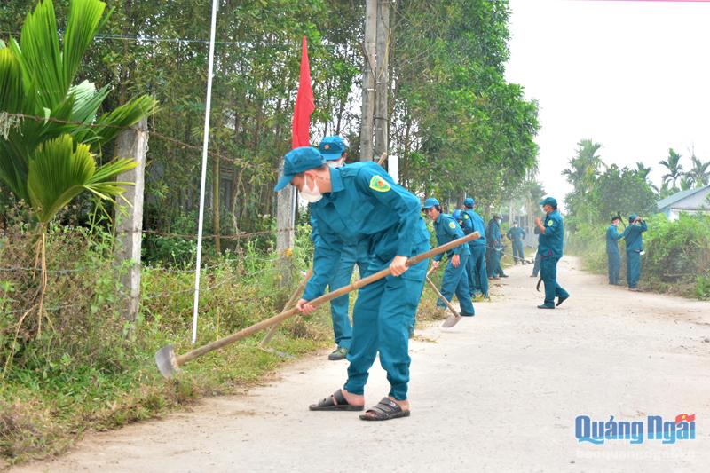 Lực lượng dân quân dọn vệ sinh môi trường, phát dọn cỏ tại tuyến đường ở thôn Đức Sơn, xã Tịnh Hiệp.