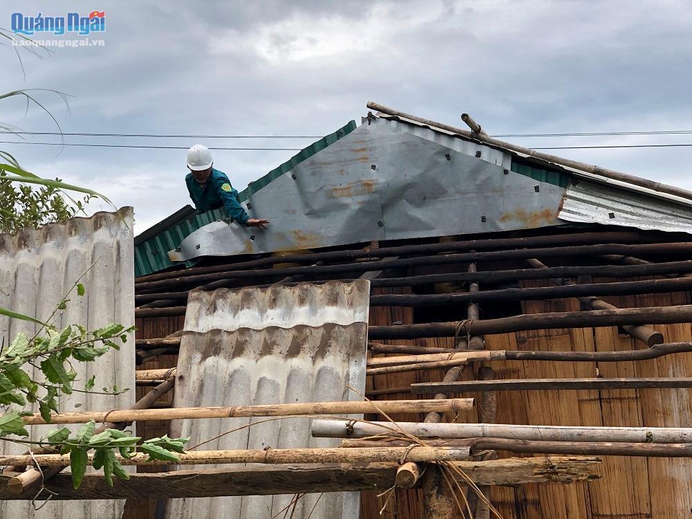 Dân quân tự vệ xã Hương Trà gia cố tôn mái nhà sau bão số 4.