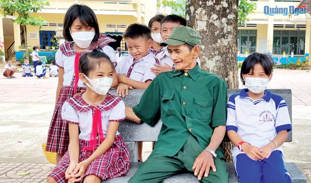 Cựu chiến binh Phạm Thanh Mong, ở xã Ba Tô (Ba Tơ) trò chuyện với học sinh Trường Tiểu học Ba Tô.                 Ảnh: Ngọc Đức