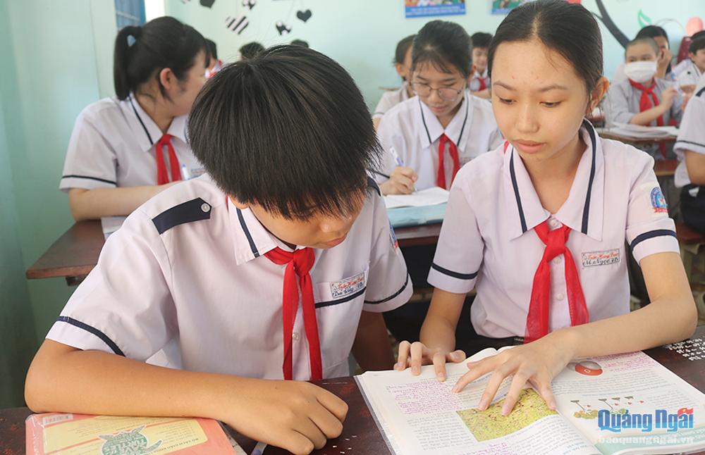 Em Nguyễn Thị Minh Ngọc, học sinh Trường THCS Trần Hưng Đạo, TP.Quảng Ngãi (bên phải) dùng giấy ghi chú dán vào sách để giữ gìn sách giáo khoa tốt hơn.