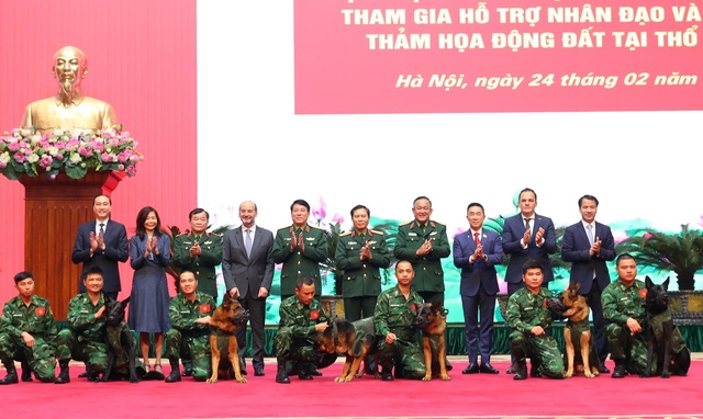 Đại tướng Lương Cường và Thượng tướng Nguyễn Tân Cương chụp ảnh chung với đội huấn luyện chó nghiệp vụ của lực lượng biên phòng. Ảnh: Trọng Đức - TTXVN